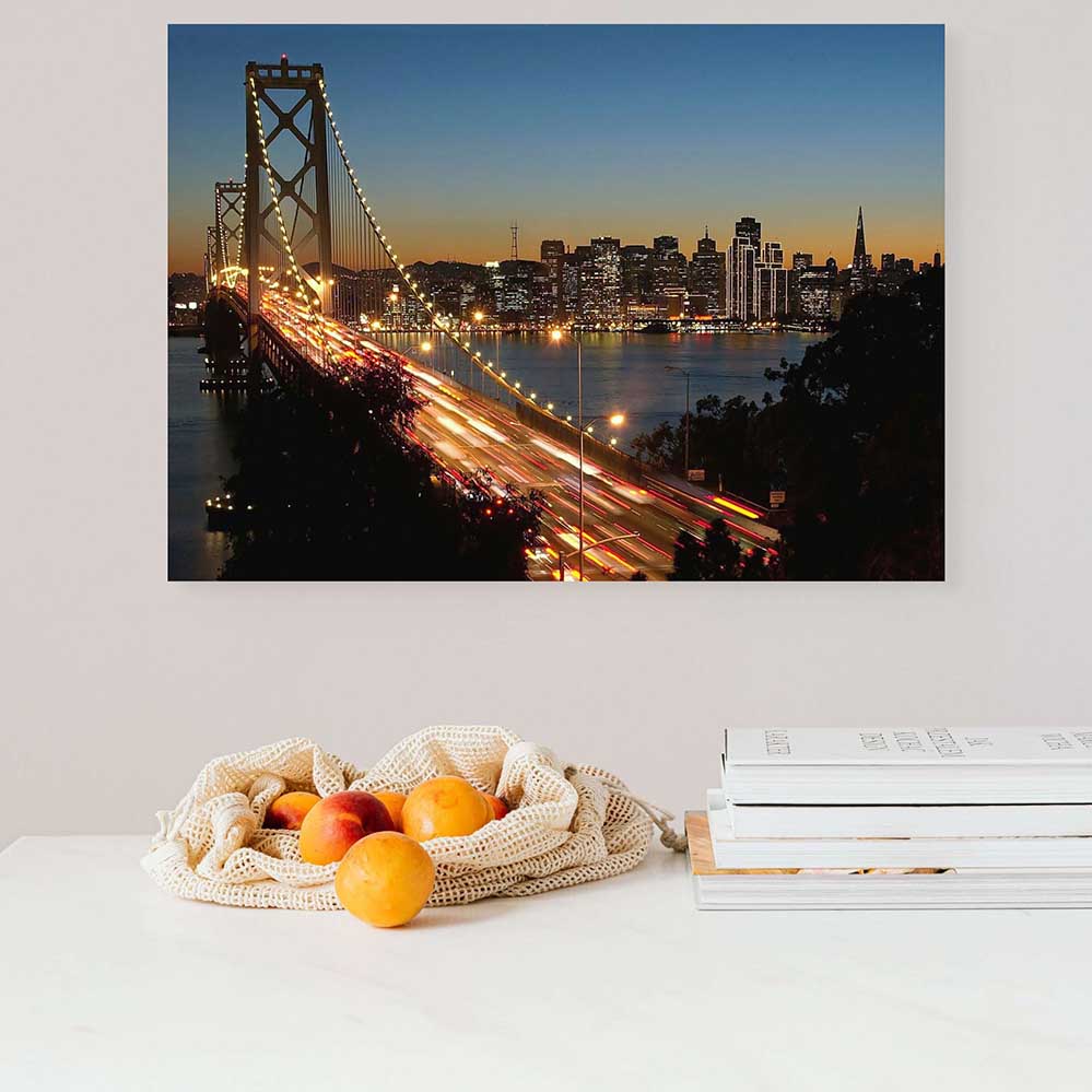 Golden Gate Bridge cityscape at dusk decal , displayed on a wall above a table with fruits and books.