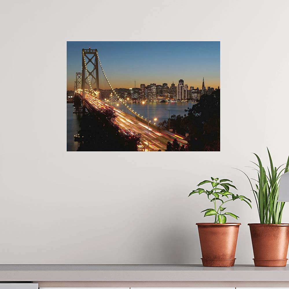 Poster of a Golden Gate Bridge with Cityscape background at dusk on a wall above a shelf with plants.
