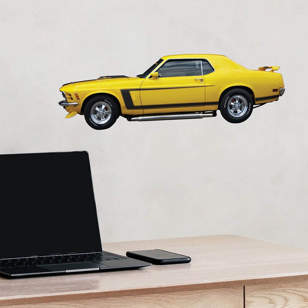 24 inch Yellow mustang muscle car decal installed on a light gray wall above a desk with a laptop and phone.