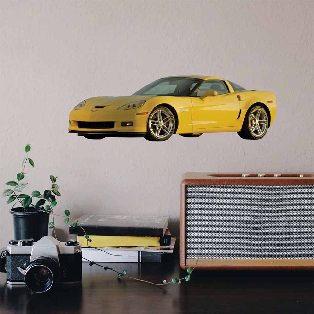 24 inch yellow Corvette Z06 decal on a wall above a table with a camera and books.