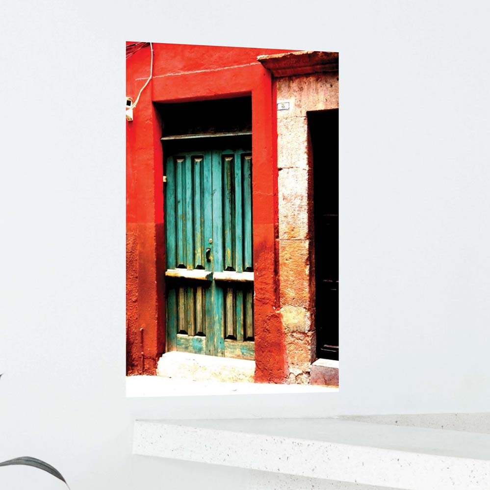 24 inch poster of a red framed green door of a Mexican home displayed on a wall above counter