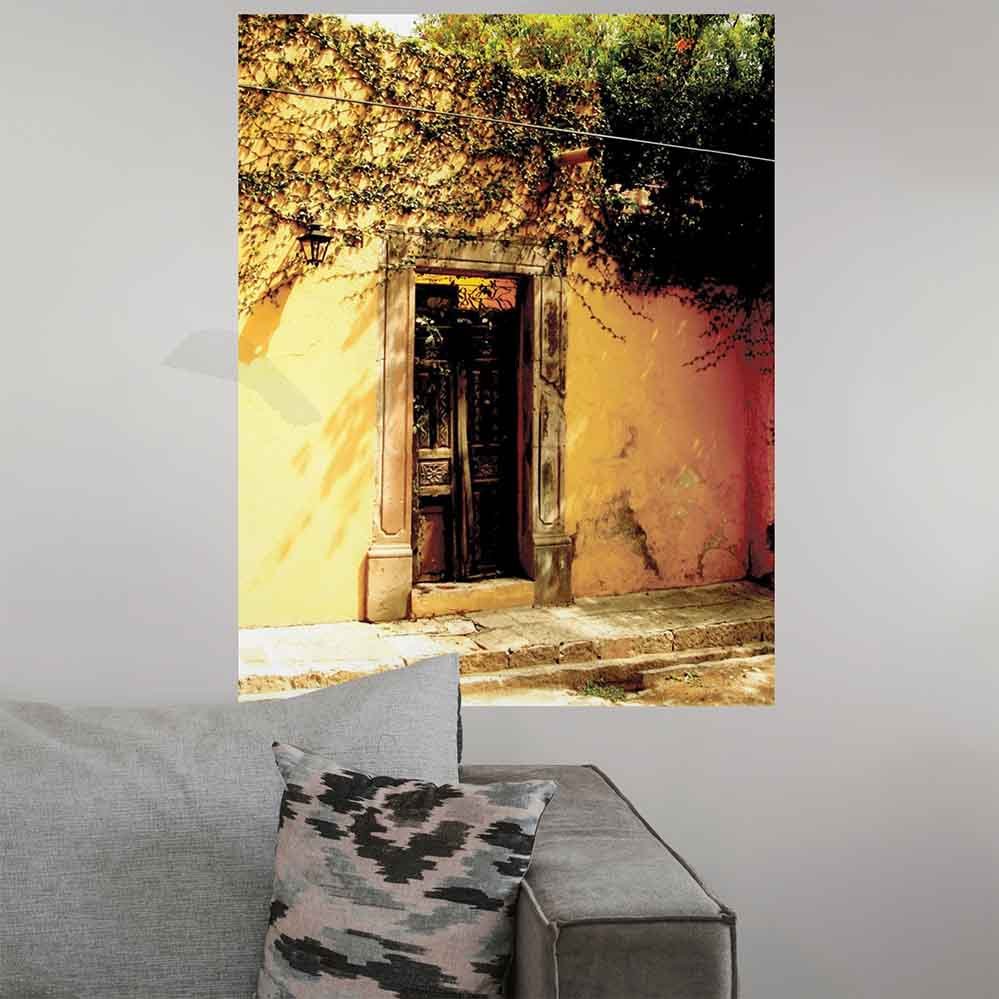 24 inch decorative wall decal of a rustic Mexican door with ivy installed on a plain wall above sofa