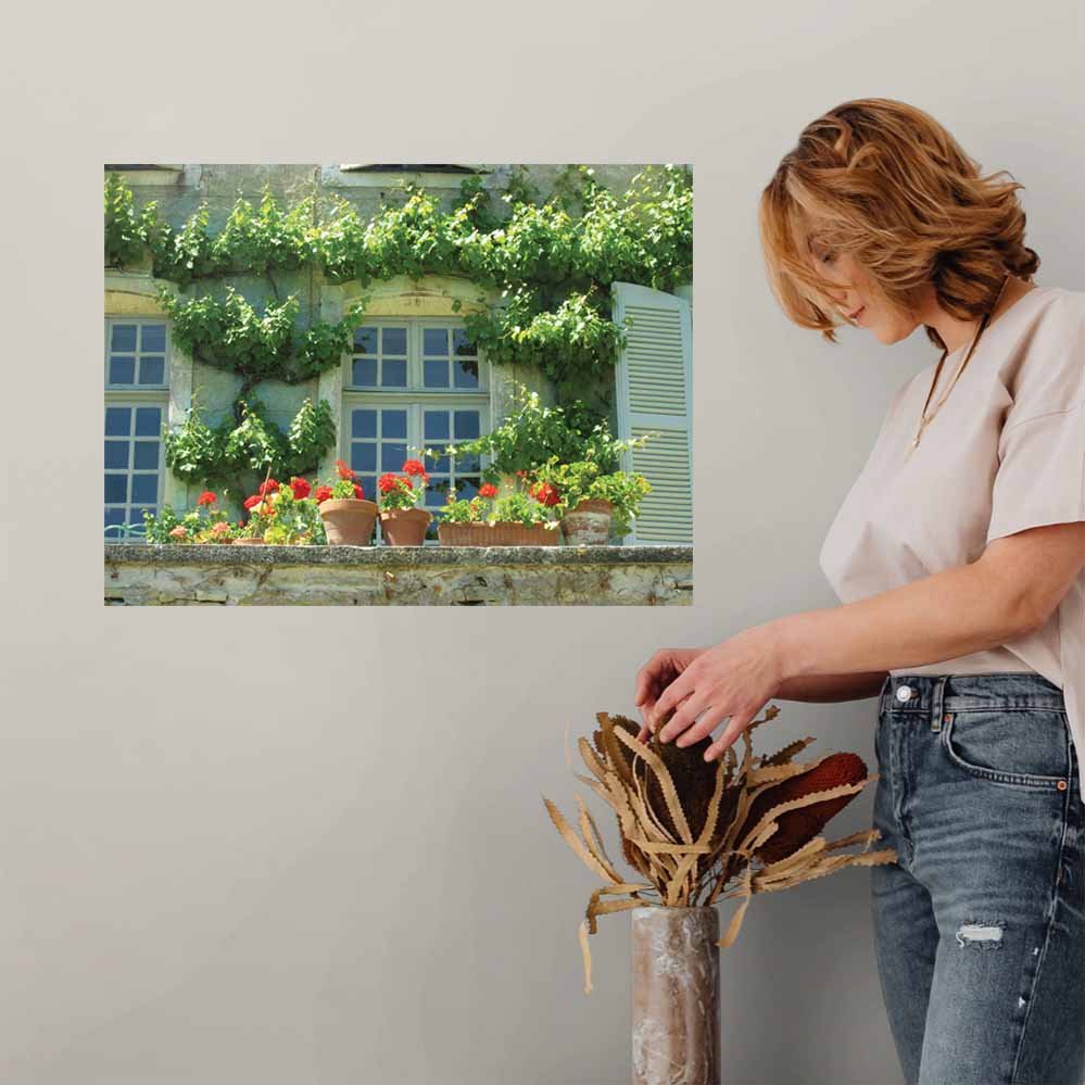 Woman arranging flowers in a vase with a decorative 24 inch wall decal of a terrance in Auvillar France with ivy and flowers