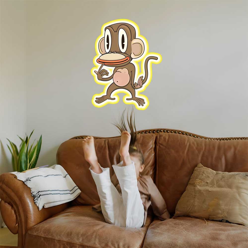 Kid on a brown couch with the 36 inch Pondering Monkey cartoon decal installed on wall above them.