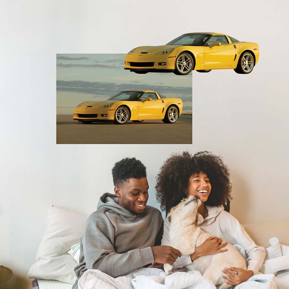 36 inch yellow Corvette Z06 poster installed on wall above two people and a dog in bed