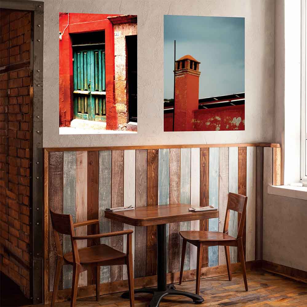 36 inch poster of a red framed green door of a Mexican home displayed on a wall above a cafe table and chairs