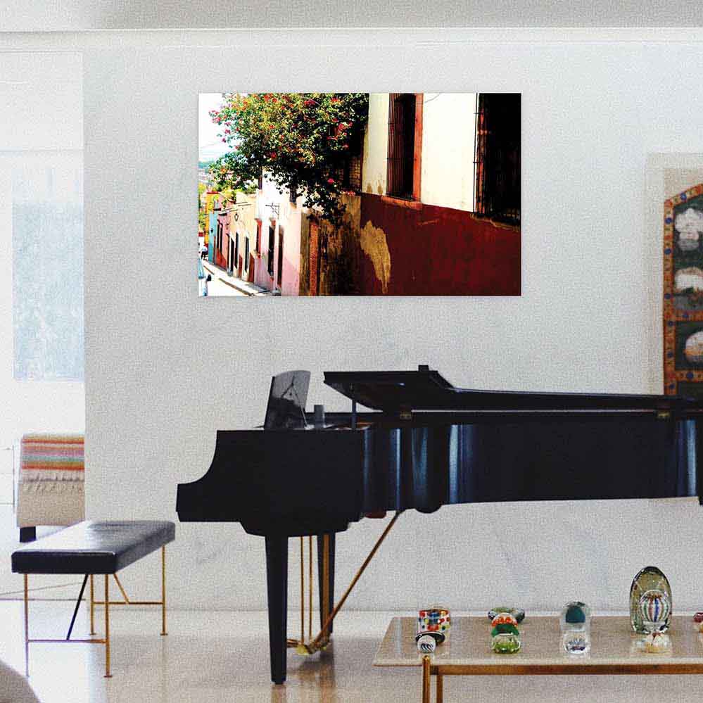 36 inch wall decal of Mexican street homes with floral bushes installed on a wall above a grand piano