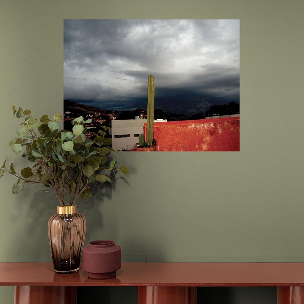 36 inch poster of a storm brewing in Mexico with a cactus in red pot in foreground displayed above console table