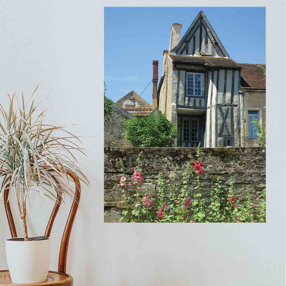 36 inch decal of a half timbered house with a wall and flowers in foreground installed on a wall next to a wicker chair