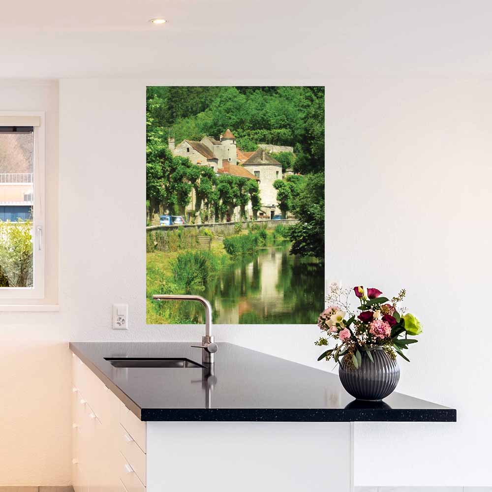 36 inch poster of a old stone building in France along a river displayed on wall above counter in kitchen