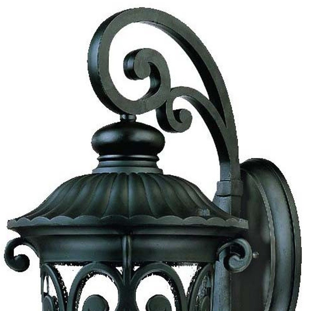 Close up view of the wall plate, scroll arm, and top of the Naples 3-Bulb Matte Black Outdoor Hanging Wall Light with Seeded Glass and Italian Scroll Design