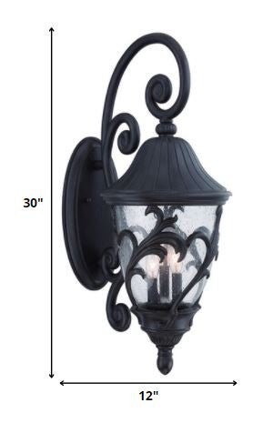 Three Light Matte Black Leaf Detail Outdoor Wall Fixture with Seeded Glass and Scroll Arm shown with dimensions of 30 inches high by 12 inches wide