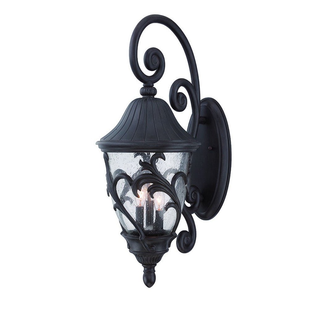 Front right view of the lighted Three Light Matte Black Leaf Detail Outdoor Wall Fixture with Seeded Glass and Scroll Arm