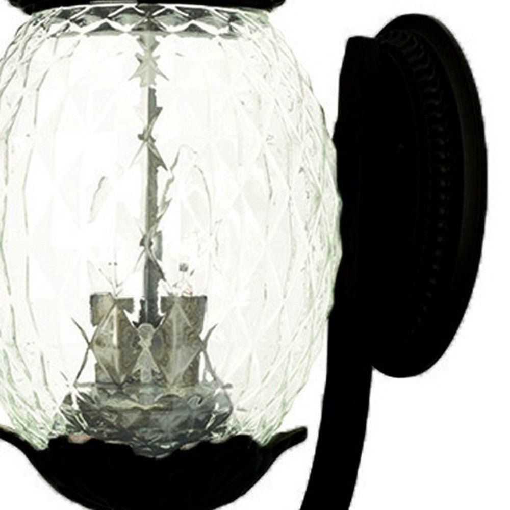 Zoomed in view of the wall plate and glass globe of the Lanai 3-Bulb Matte Black Upward Outdoor Wall Light with Pineapple Textured Glass