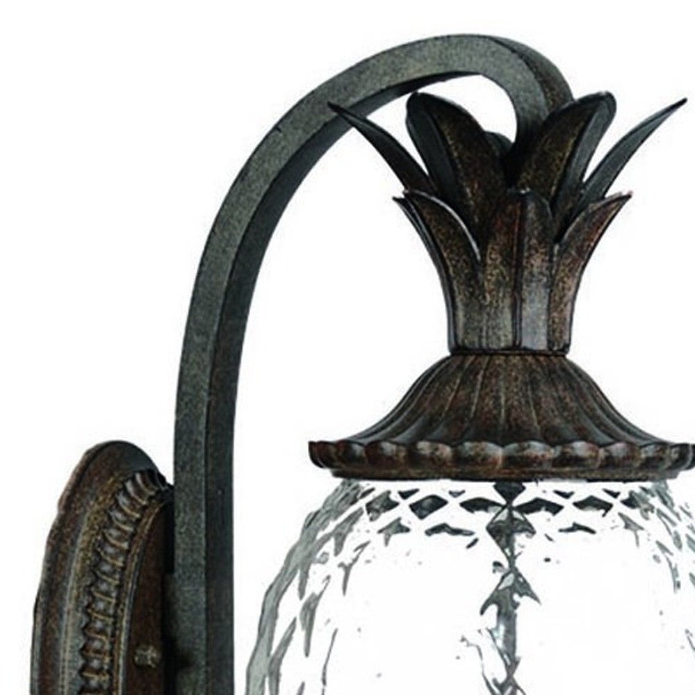 Zoomed in view of the curved arm, pineapple top and textured glass of the Lanai 3-Bulb Black Coral Outdoor Wall Lantern with Pineapple Design and Textured Glass