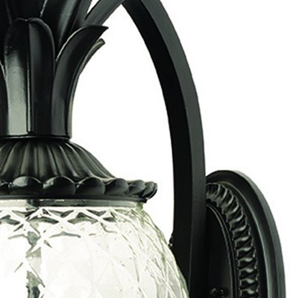 Close up view of the hammered glass, wall plate, and arm of the Lanai 3-Bulb Matte Black Outdoor Wall Lantern with Pineapple Design and Textured Glass
