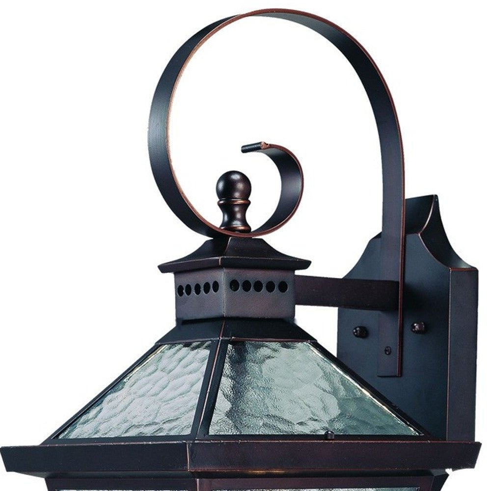Zoomed in view of the wall plate, swirl arm and lantern top of the Bay Street Triple-Light Architectural Bronze Outdoor Wall Lantern with Hammered Glass