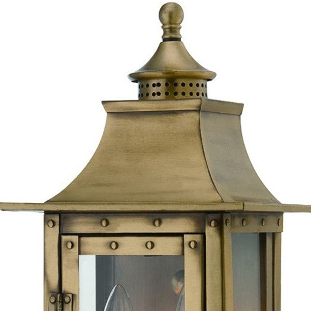 Zoomed in view of the lantern top with rivets of the lighted St. Charles 2-Bulb Aged Brass Colonial Outdoor Wall Lantern Light
