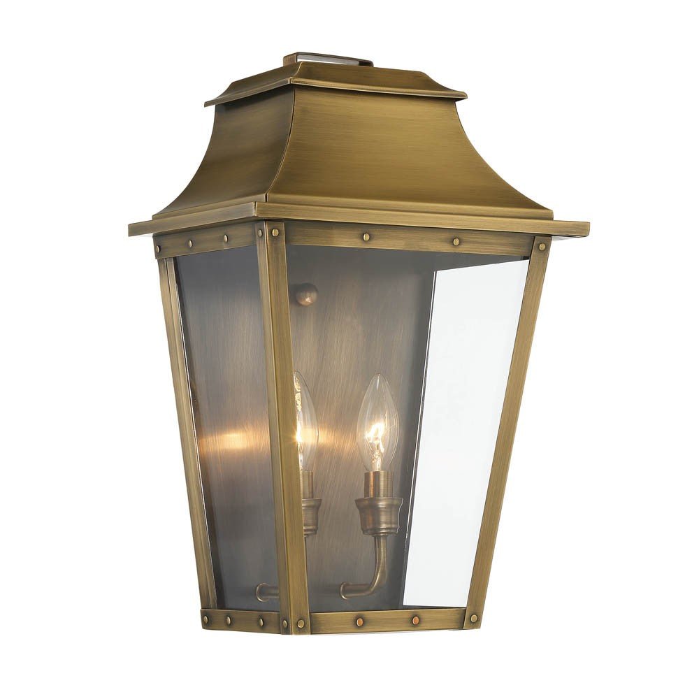 Front left side angle view of the lighted Coventry 2-Bulb Aged Brass Pocket Wall Lantern with Clear Glass Panels – Outdoor Indoor Lighting Fixture