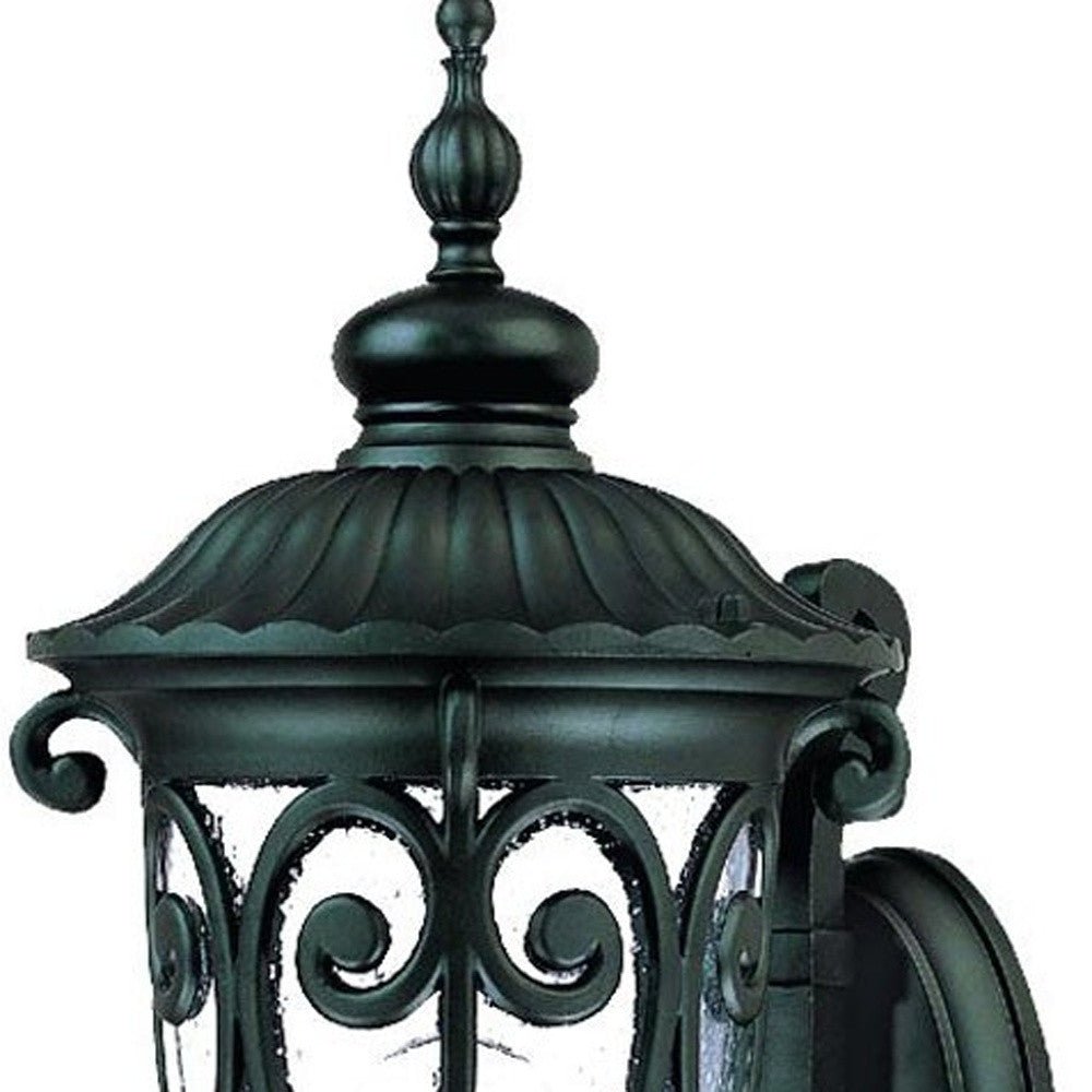 Zoomed in view of the fixture top and glass shade of the Naples Matte Black Outdoor Wall Lantern with Seeded Glass and Scroll Design
