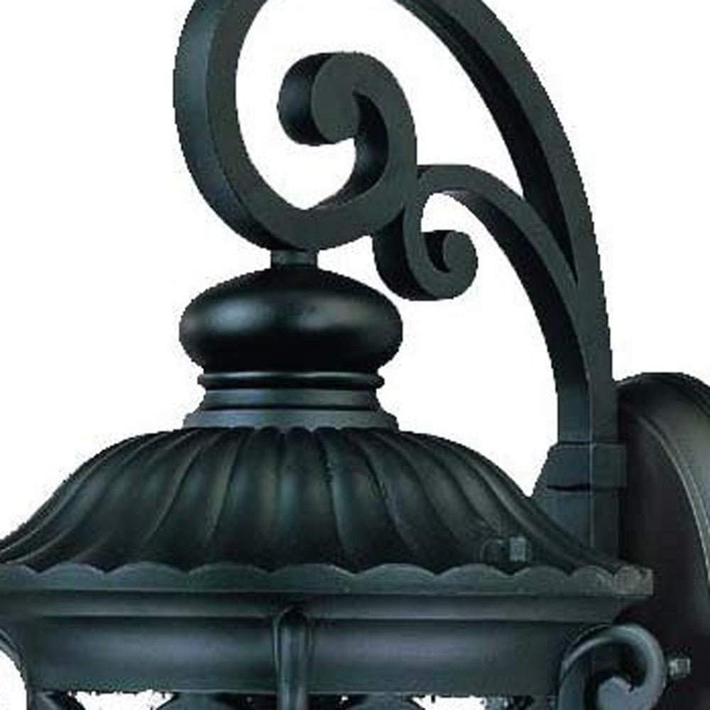 Zoomed in view of the fixture top of the Naples matte black outdoor wall lantern with ornate scrollwork and seeded glass shade