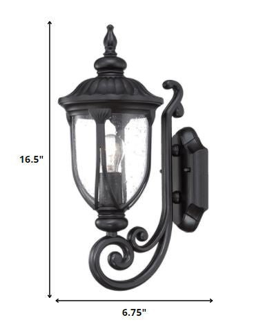 Matte black cast aluminum outdoor glass lantern wall light with clear panels shown with dimensions of 16 point 5 inches high by 6 point 75 inches wide