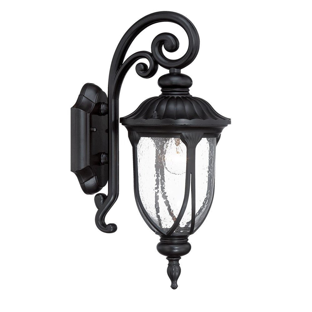 Left side angled view of he lighted Matte black cast aluminum outdoor glass lantern wall sconce with clear panels