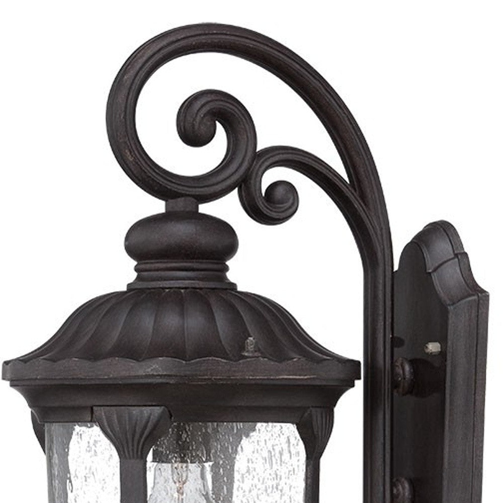 Zoomed in view of the wall plate, scroll arm, and top of fixture of the XL black cast aluminum outdoor hanging lantern wall sconce with clear glass panels