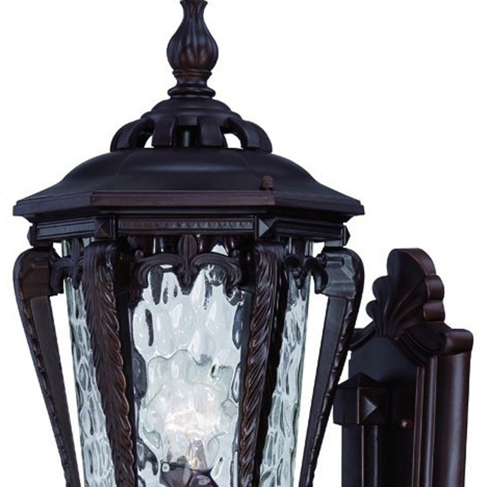 Zoomed in view of the wall plate, and top half of fixture of the Architectural bronze outdoor wall light with hammered glass and scroll detailing