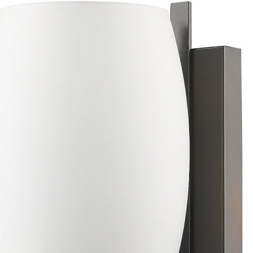 Zoomed in view of the wall plate and glass shade of the  Geometric bronze wall sconce with frosted glass shade for modern indoor lighting in hallways, bedrooms, and living spaces.
