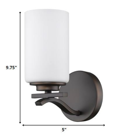 One-light bronze wall sconce with frosted cylindrical glass shade and curved metal arm shown with dimensions of nine point seven five inches high by five inches wide