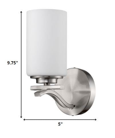 One-light brushed silver wall sconce with curved arm and frosted cylindrical glass shade shown with dimensions of nine point seven five inches high by five inches wide