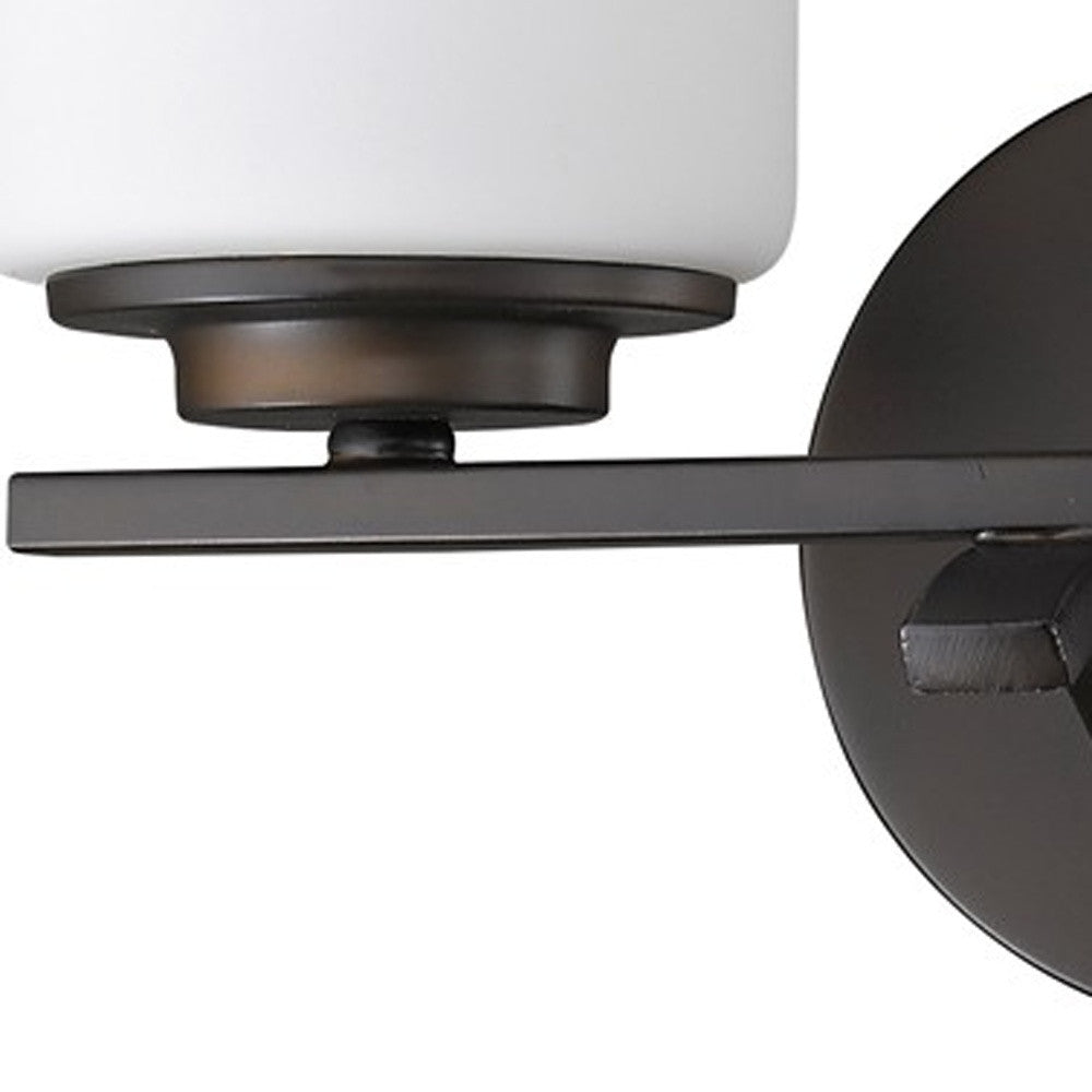 Zoomed in view of the wall plate, arm and glass shade of the Two-light bronze wall sconce with cylindrical frosted glass shades and round base plate