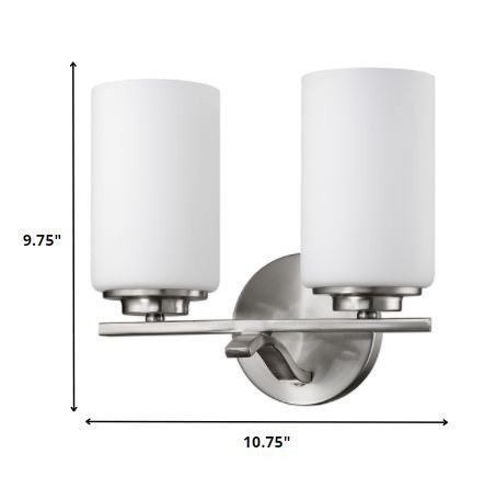 Two-light brushed silver wall sconce with frosted cylindrical glass shades and modern round backplate shown with dimensions of nine point seven five inches high by ten point seven five inches wide