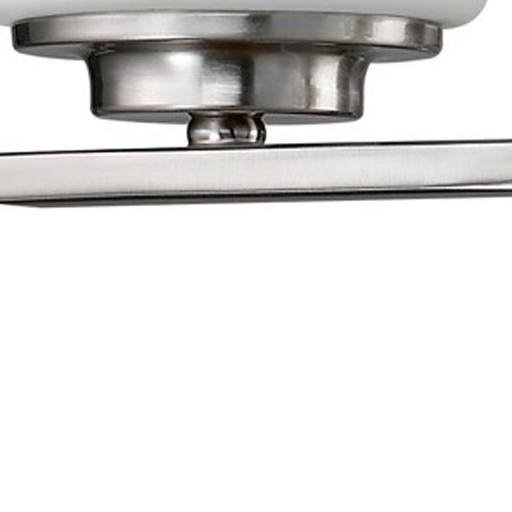 Zoomed in view of the arm and shade base of the Two-light brushed silver wall sconce with frosted cylindrical glass shades and modern round backplate