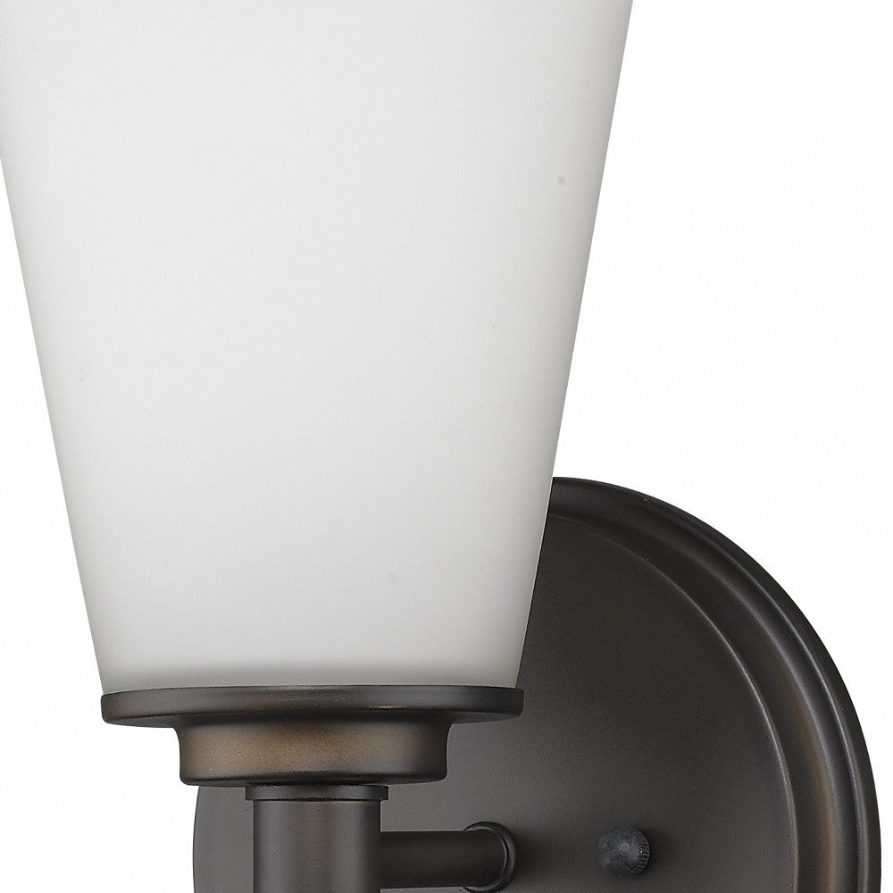 Zoomed in view of the wall plate, arm and glass shade of the Single bronze wall light with tapered frosted glass shade and round backplate