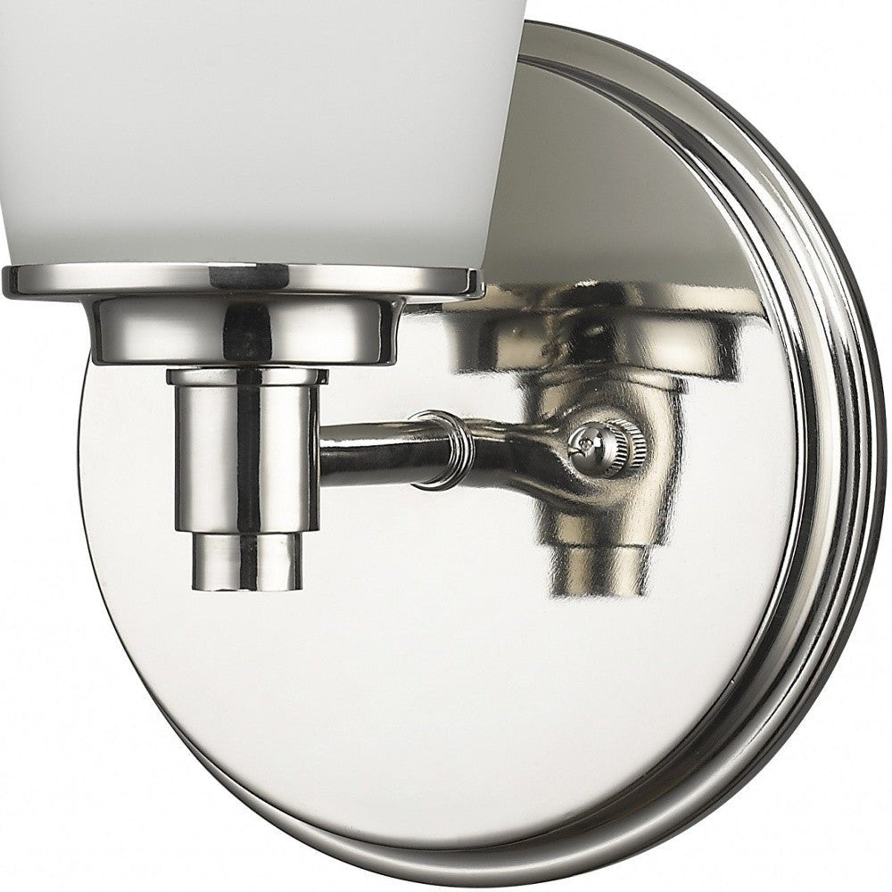 Zoomed in view of the backplate, arm and glass shade of the Single silver wall light with tapered frosted glass shade and round backplate
