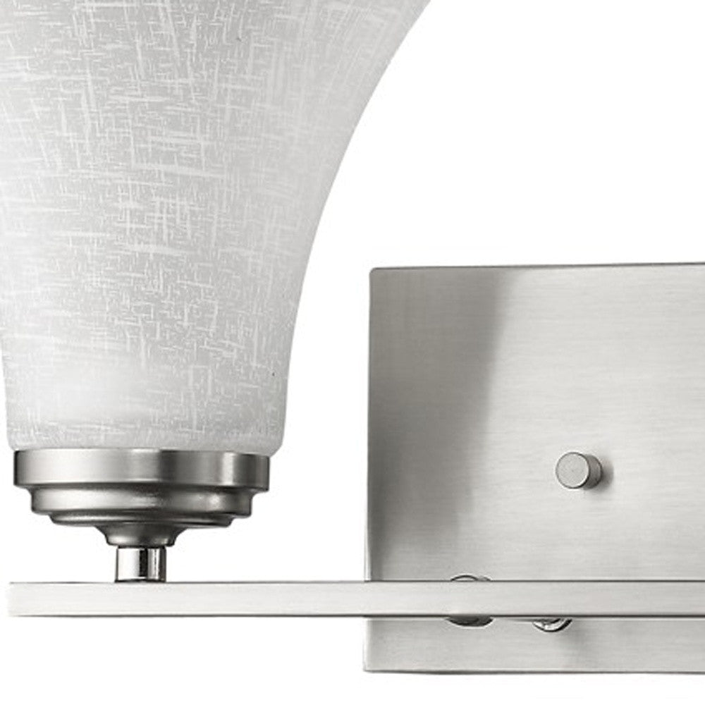Zoomed in view of the wall plate, arm and glass shade of the Two-light silver wall fixture with tapered textured glass shades and modern rectangular backplate