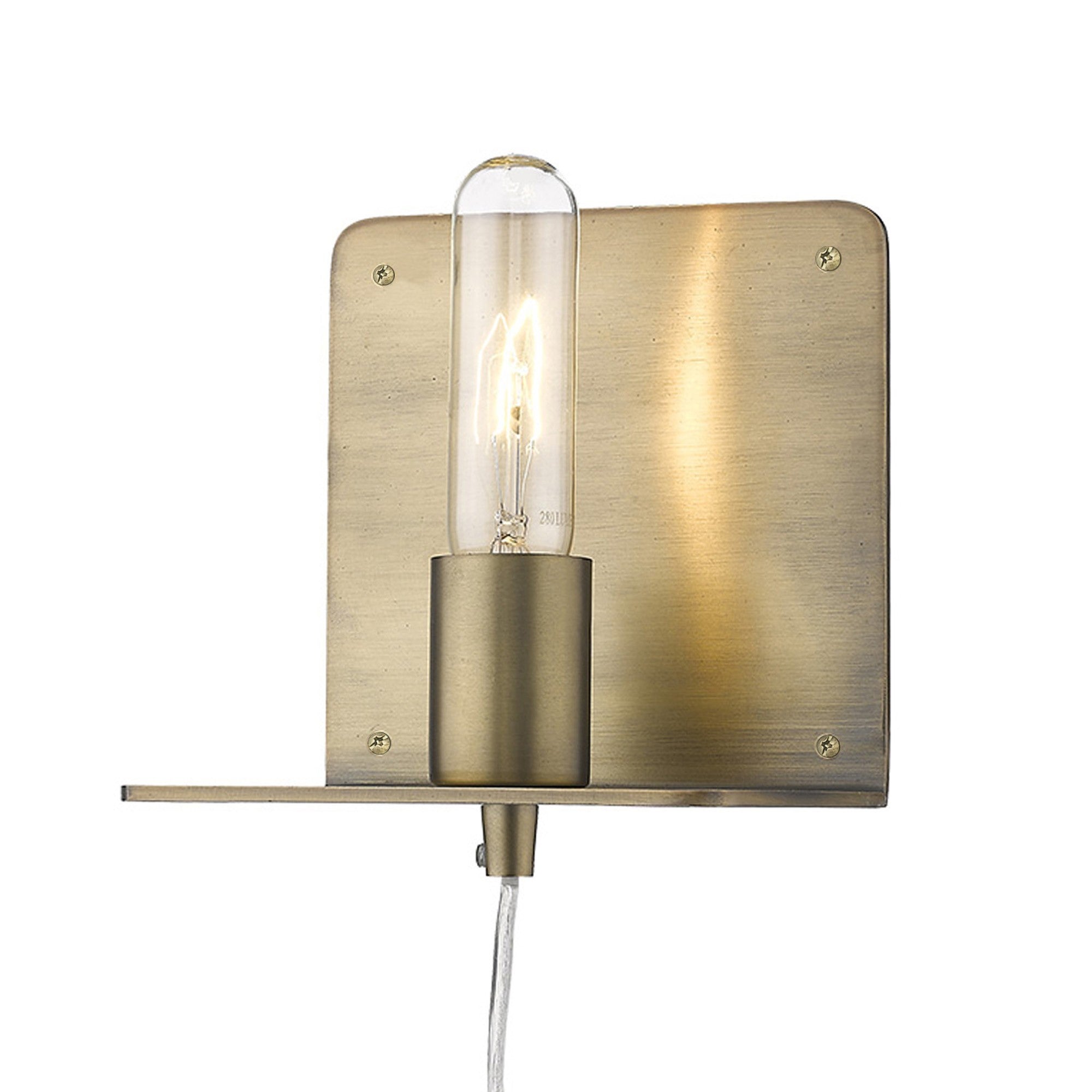 A angled view of a dull gold Petite Shelf Wall Light with a clear glass bulb and a shelf below, mounted on a wall.