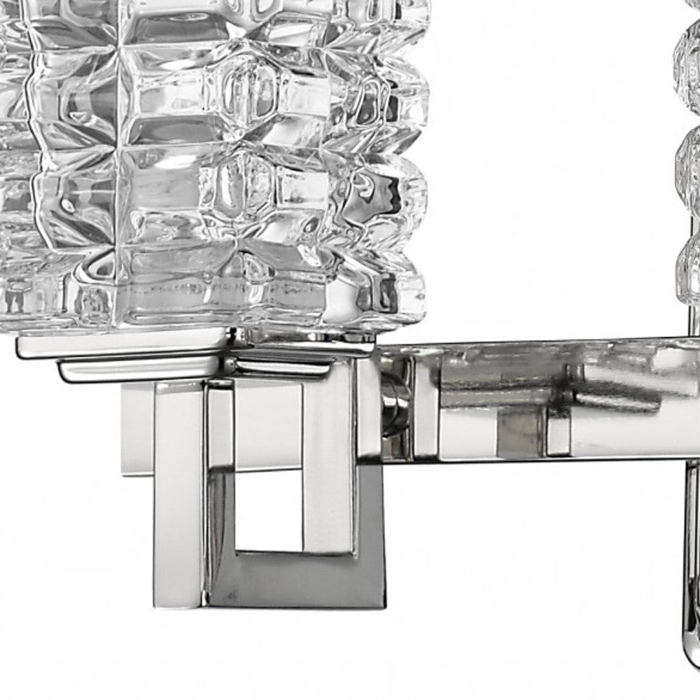 Zoomed in view of one of the glass shades and arm of the Coralie Three-light chrome vanity wall fixture with geometric crystal glass shades