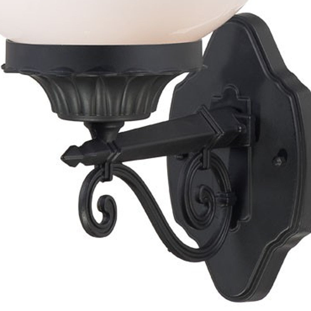 Close-up of decorative scroll arm and mounting plate of vintage black wall sconce with globe shade