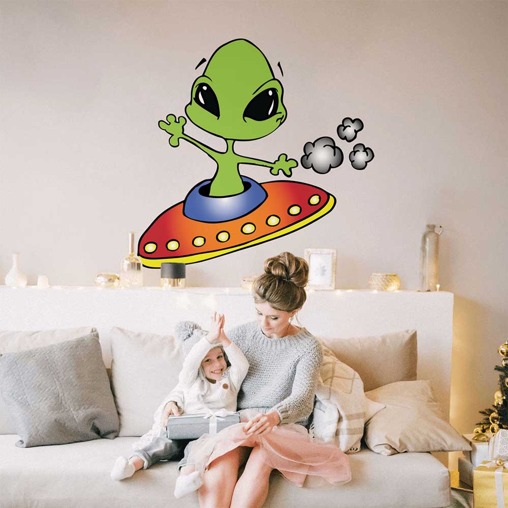 Woman and child sitting on a couch with a 46x48 inch wall decal of an alien on a UFO.