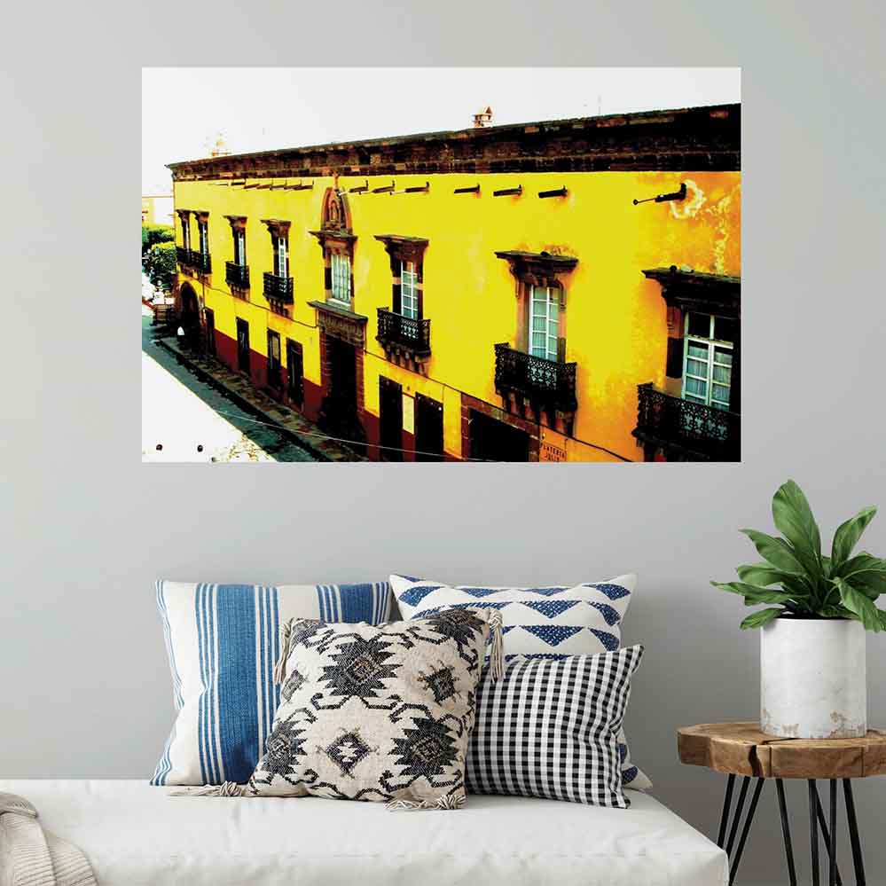 48 inch yellow Mexican hotel with balconies displayed on a wall above a daybed with pillows