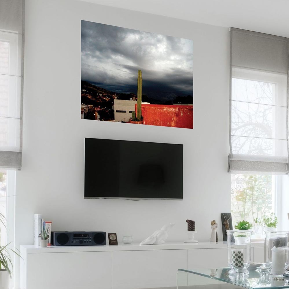48 inch poster of a storm of gray clouds in Mexico with potted cactus in foreground displayed on wall above TV