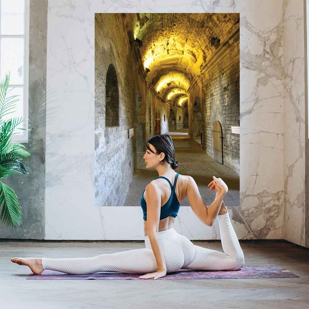 24 inch decal of a long, narrow hallway with arches in Nimes France Roman Arena installed on wall with a woman doing yoga in foreground