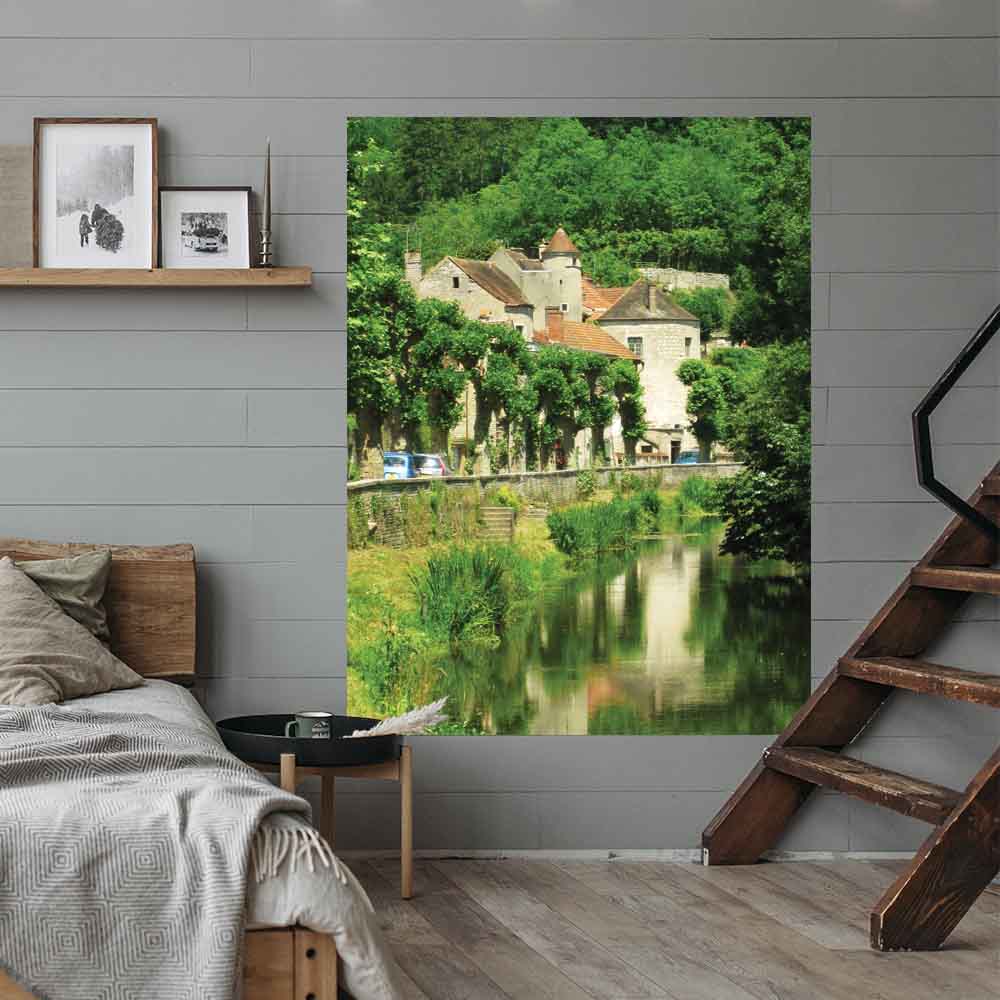 48 inch poster of a old stone building in France along a river displayed on wall in bedroom next to wooden stairs