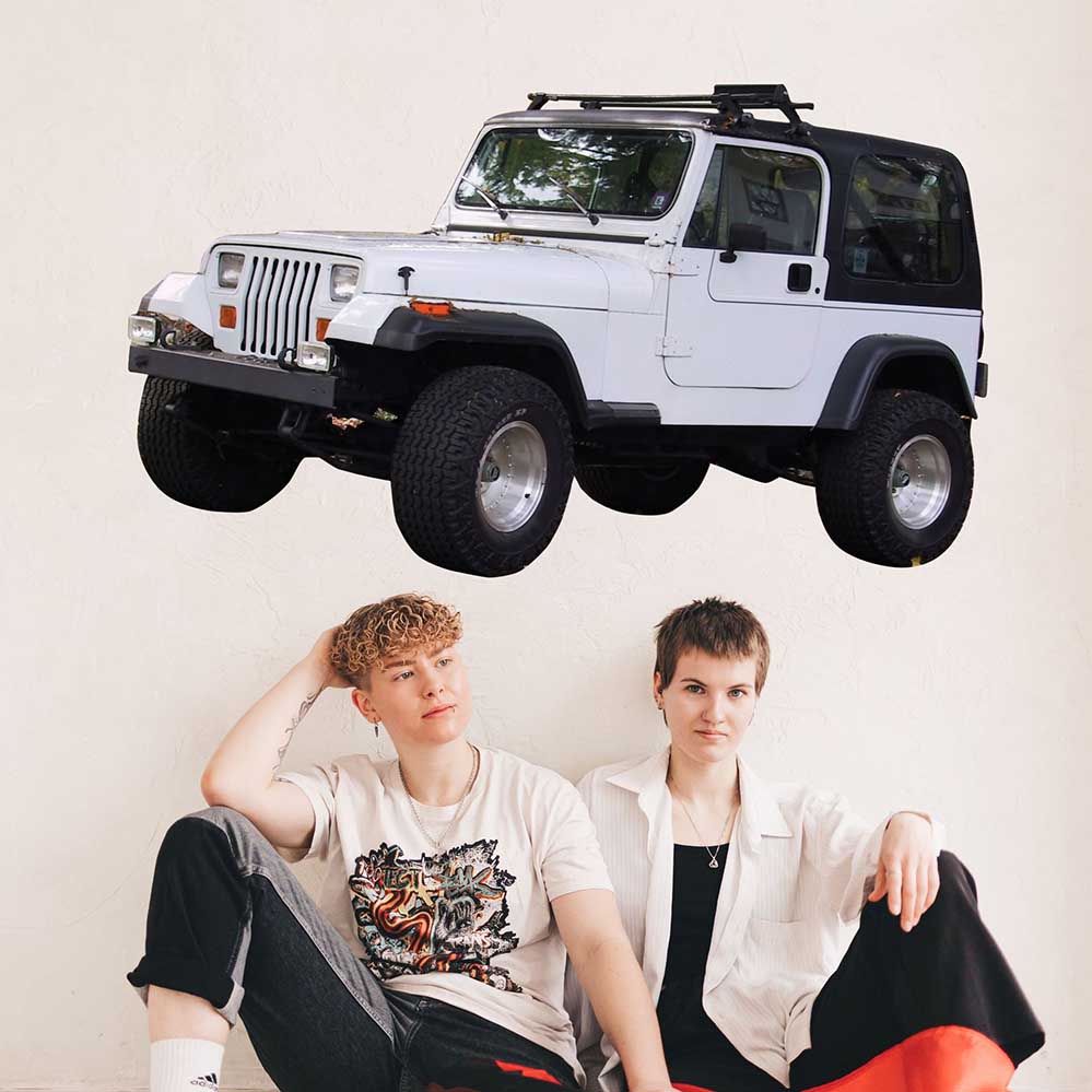 Two teens sitting on the floor with a 60 inch white Jeep decal installed on wall above them