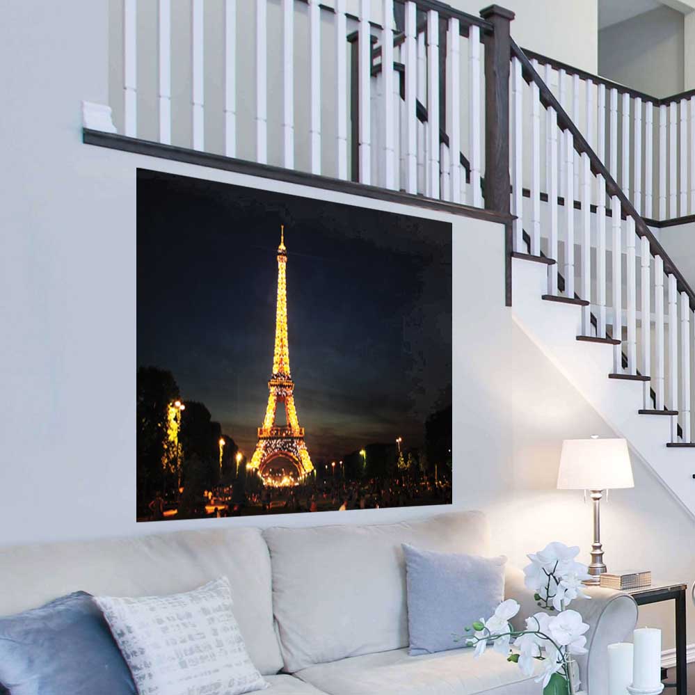 60 inch decal of the illuminated Eiffel Tower at nigh against a dark sky installed on a wall Above a sofa