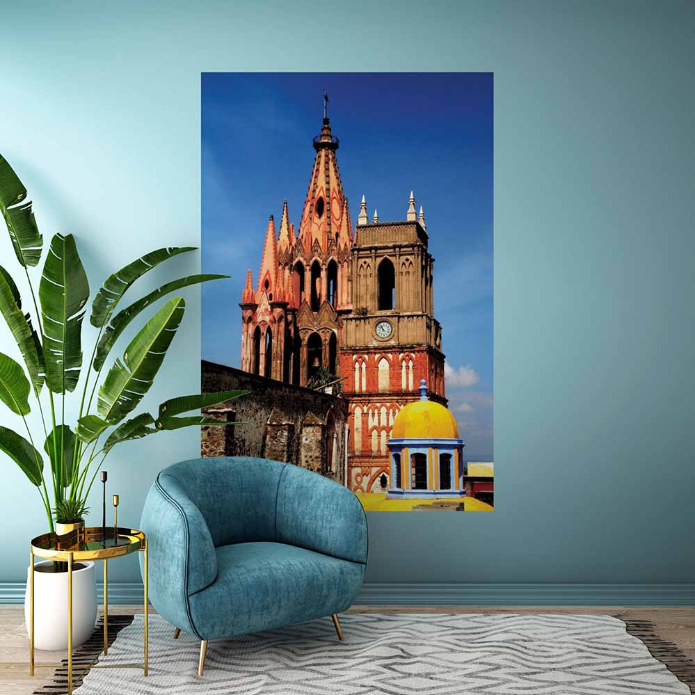 72 inch decal of a colorful Mexican cathedral installed on a wall with blue chair and plant in the foreground