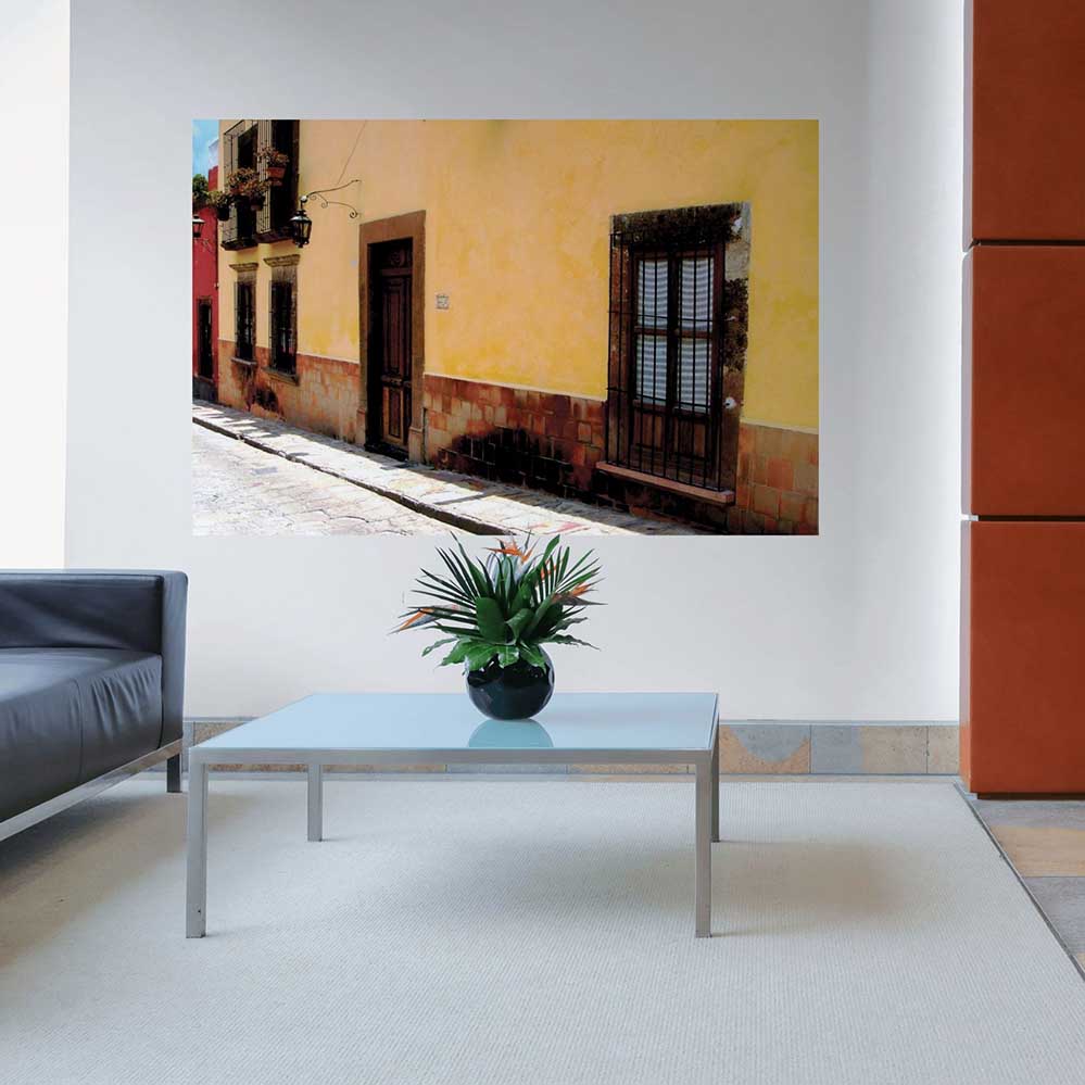 72 inch poster Mexican street and yellow house architecture displayed on a wall in a living room